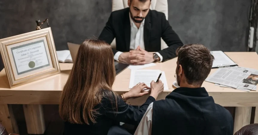Professional advisor discussing asset protection trust strategies with two clients at office desk meeting.