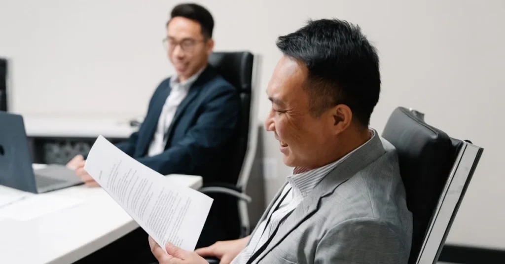 Two professionals reviewing asset protection trust documents during business meeting discussion.