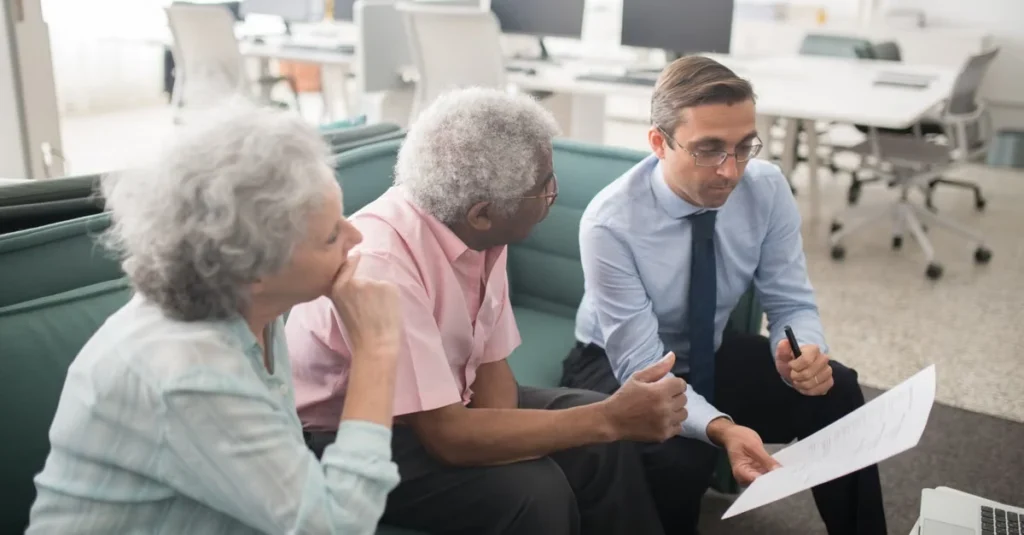 Financial advisor discussing asset protection trust strategy with senior couple in modern office.