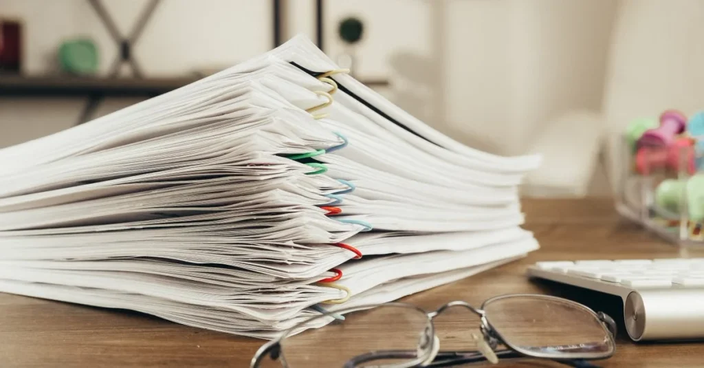 Stack of organized documents with colorful clips on desk, representing essential estate planning tools.