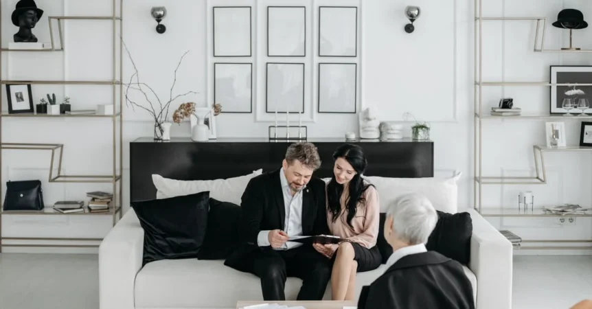 Three professionals reviewing documents on modern white sofa in minimalist office, discussing estate planning attorney.