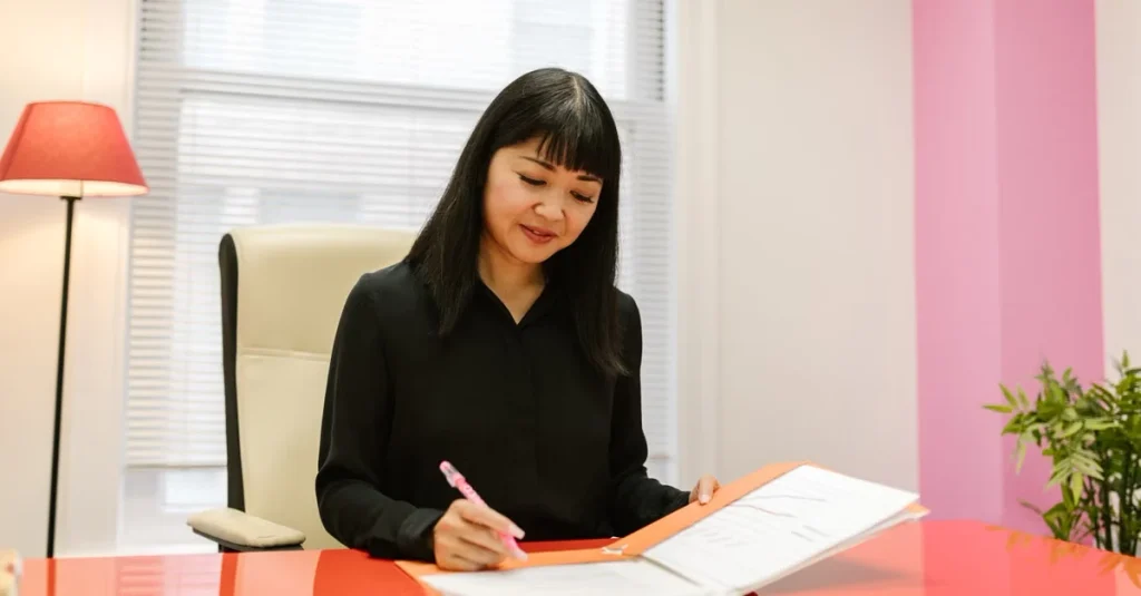 Woman in black blazer writing on document at desk, planning estate planning legacy strategy.
