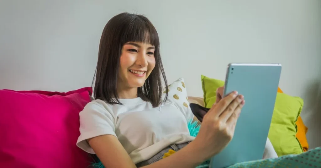 Woman smiling while using tablet on colorful couch, exploring estate planning attorney resources online.