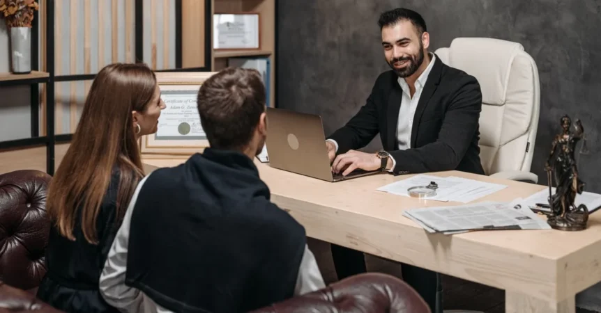 Estate planning attorney meeting with clients at desk to discuss legal services and questions.