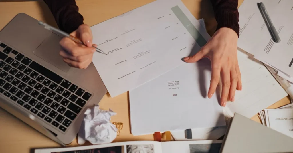 Person reviewing estate planning documents with laptop and sketches at desk for legal consultation.