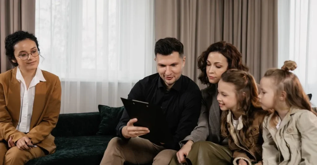 Family reviewing financial documents with advisor on couch during high net worth estate planning consultation meeting.