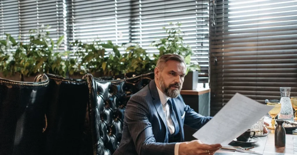 Businessman reviewing business sale documents at desk before selling company.